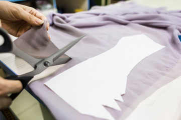 Sewing workshop. Seamstress at work. Marking and cutting fabric.