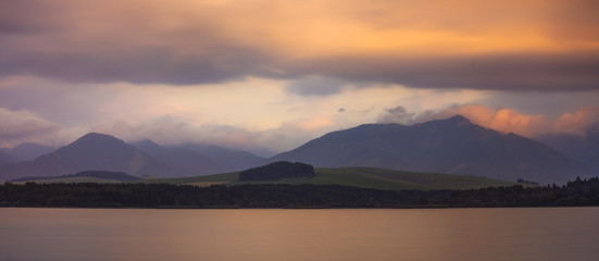 Naklejka na ściany i meble Long Exposure Shot of Lake, Mountains and Cloudy Sky at Sunset. Liptovska Mara, Slovakia