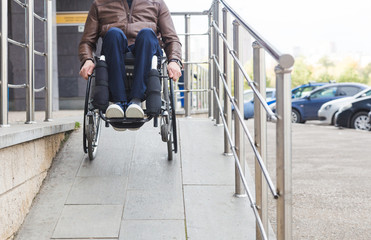 Man in a wheelchair use a wheelchair ramp.