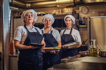 Cooking team posing for a camera at restaurant's kitchen.