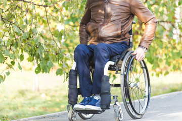Obraz premium A young man in a wheelchair rides along the park road.
