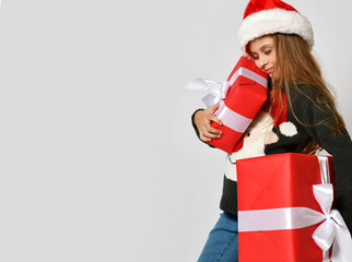 Little girl kid in x-mas santa helper hat with red gift boxes happy smiling shouting
