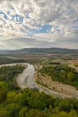 Fototapeta na wymiar Aerial view of a river with woods, cultivated fields and hills in the background in autumn, Langhe, Piedmont, Italy