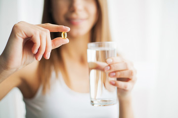 Vitamins and Supplements. Woman taking a tablet. Close up hand with a pill and the mouth.