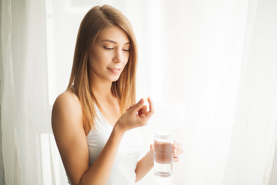 Vitamins and Supplements. Woman taking a tablet. Close up hand with a pill and the mouth.