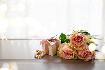 Rose fresh flowers bouquet on gray table by the window with gift box and bokeh lights