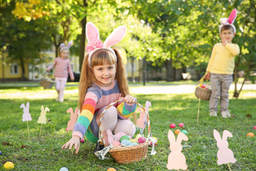Cute little children hunting eggs in park. Easter tradition