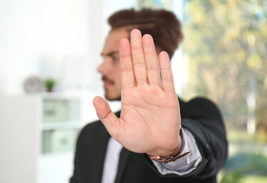 Man showing stop gesture in office. Problem of sexual harassment at work