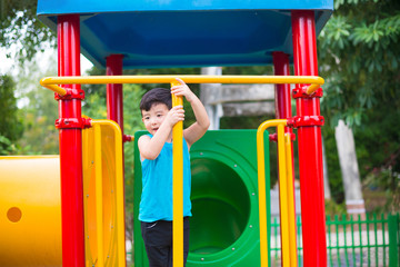 Asian kid playing at the playground under the sunlight in summer, Happy kid in kindergarten or preschool school yard.