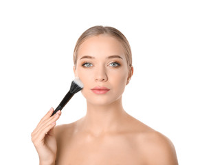 Portrait of beautiful young woman with makeup brush on white background