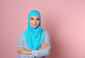 Portrait of young Muslim woman in hijab against color background