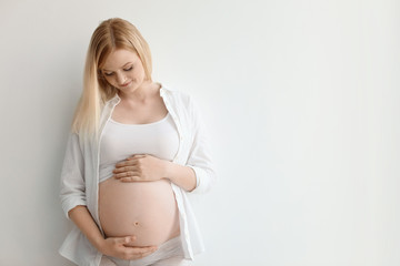 Portrait of beautiful pregnant woman on light background. Space for text