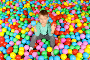 Fototapeta na wymiar Cute child playing in ball pit indoors