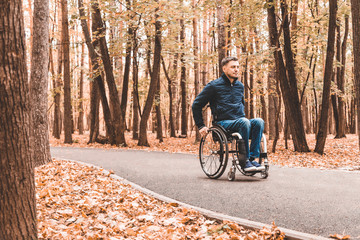 Fototapeta premium A young man in a wheelchair rides along the park road.