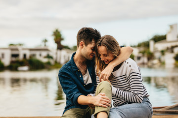 Couple in love sitting outdoors near a lake
