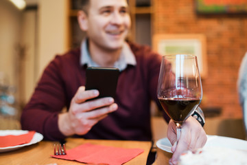 Young man having lunch. Dinner table, holding a smartphone, checking the e- mail and sharing the news with friends