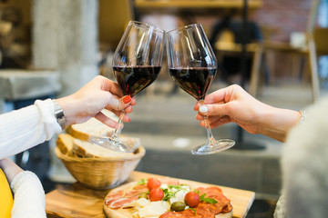 woman hands toasting with glasses of red wine