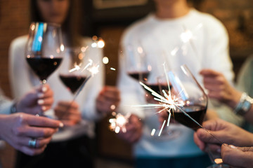group of people holding a glasses of red wine and sparkles