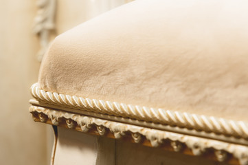 Fototapeta na wymiar Close-up element of the textile decoration of a soft bedside chair in the bedroom. Luxury furniture in vintage style