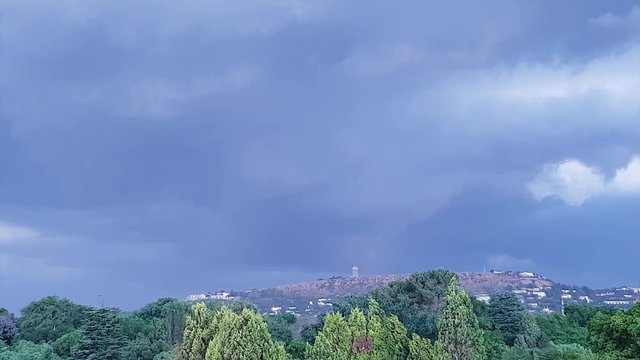 Thunder strikes as large storm clouds move across Northcliff Johannesburg Gauteng South Africa. Wind blows and moves the trees in the foreground - A storm is coming. Camera pans left along horizon.