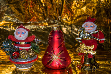 Two Santa Claus and a Christmas bell, on a gold background.