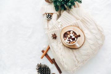 Flat lay hot cocoa with marshmallow ant knitted sweater with christmas decorations. Cozy holiday concept