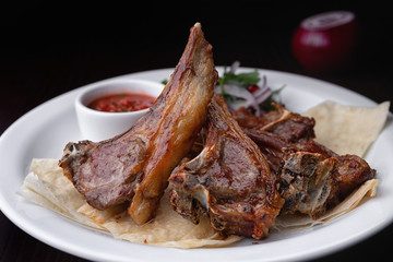 Fried Ribs on a white plate with sauce and onions