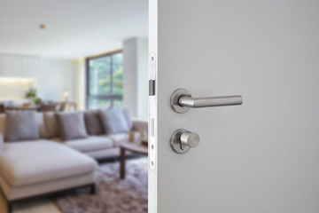 Door handle ,hotel or apartment door open in front of blur living interior room background, selective focus - obrazy, fototapety, plakaty