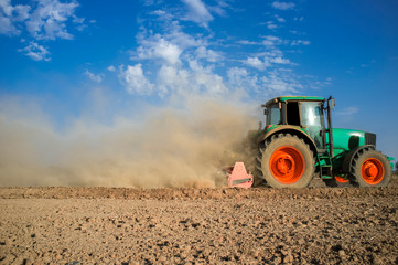 Farm tractor preparing dusty soil affected by drought