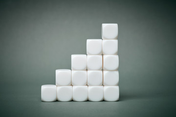 White cubes stacked in stair pyramide step by step on grey colored background