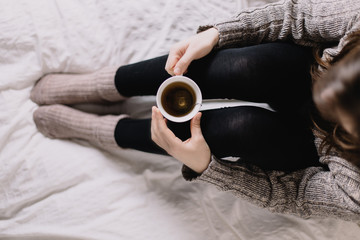 Woman sitting on bed, drinking tea