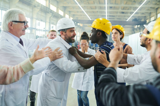 Side View  Portrait Of Angry Factory Worker Fighting With Managers During Protest In Industrial Workshop