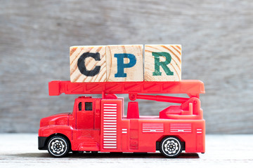 Toy fire ladder truck hold letter block in word CPR (abbreviation of Cardiopulmonary resuscitation)  on wood background