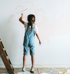Young girl painting the walls pink