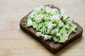 Avocado toast with feta cheese on wooden background