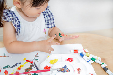 手に絵具を塗り遊ぶ幼い女の子。育児、子育て、教育、知育イメージ
