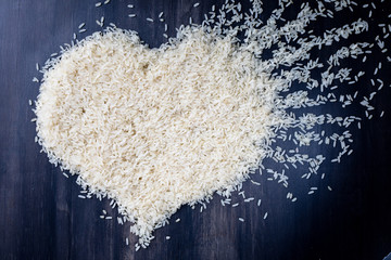 top view heart symbol of parboiled rice on black background