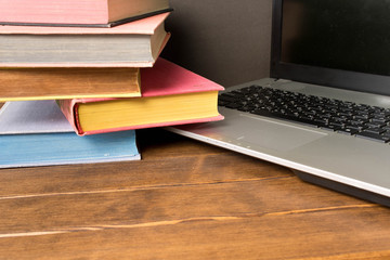Books and laptop on wooden table. The concept of learning from books or from the Internet