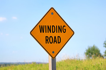 A winding road sign against a blue sky