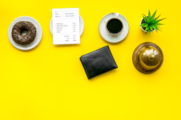 Pay the bill, pay at restaurant. Check near wallet, service bell, coffee on yellow background top view space for text