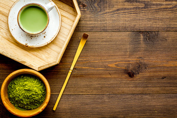Coffee and cocktails with matcha concept. Matcha latte near bowl with matcha powder and accessories on dark wooden background top view copy space