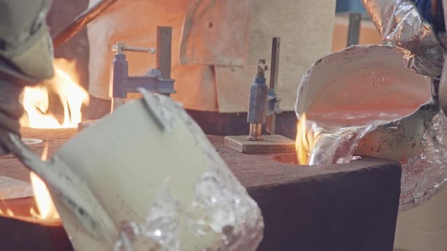 Workers in a foundry pouring liquid Aluminum to a sand cast