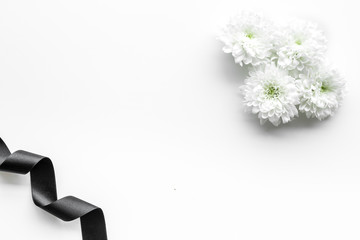 Funeral symbols. White flower near black ribbon on white background top view copy space