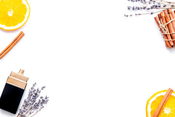 Fruity perfume for women. Bottle of perfume near orange, lavender, cinnamon on white background top view copy space border