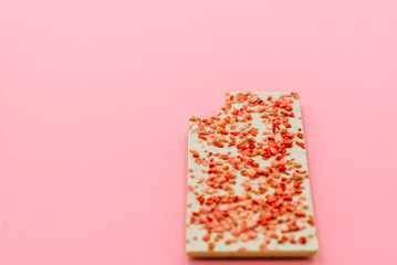 Chocolate bar with dried strawberry on a pink abstract background.