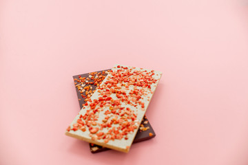 Chocolate bar with dried strawberry on a pink abstract background.