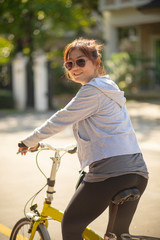 woman wearing sport clothes toothy smiling face on  mini bicycle