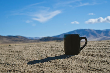 The solo blank black coffee cup on the sand dunes in the basin sun light. 