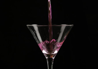 pink cocktail poured into a glass on a dark background.