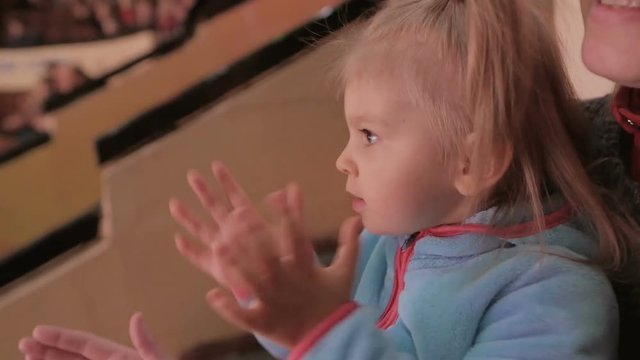 Little girl applauds looking at a circus performance